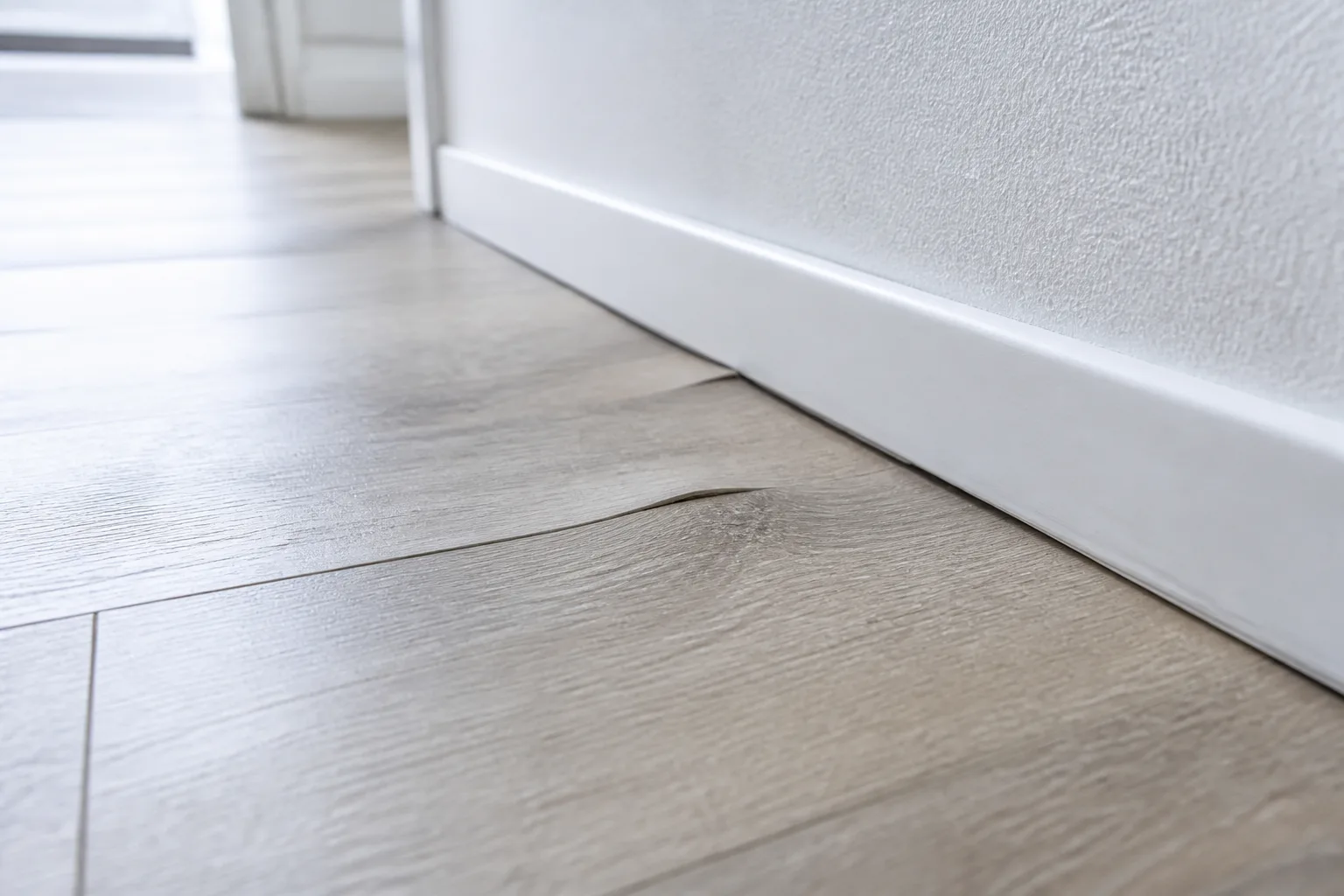 Detailaufnahme einer Bodenwelle nahe Sockelleiste.